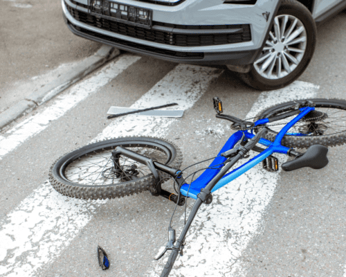 A bicycle on the ground by a car.