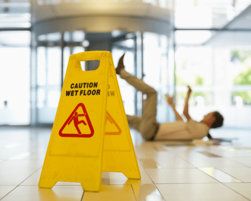 A man on the floor with wet floor sign in the foreground.